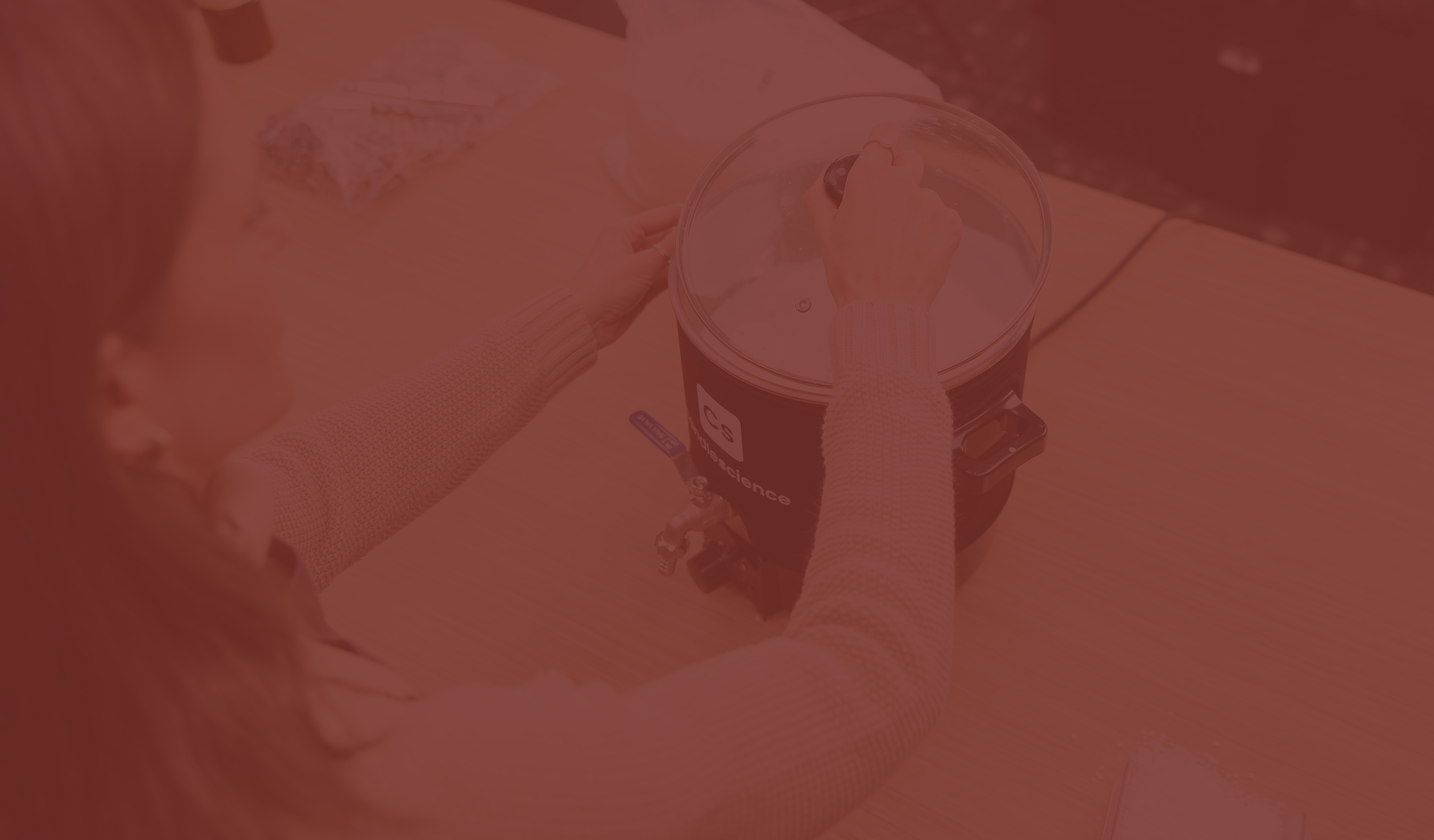 A light-skinned hand places a lid onto a wax melter