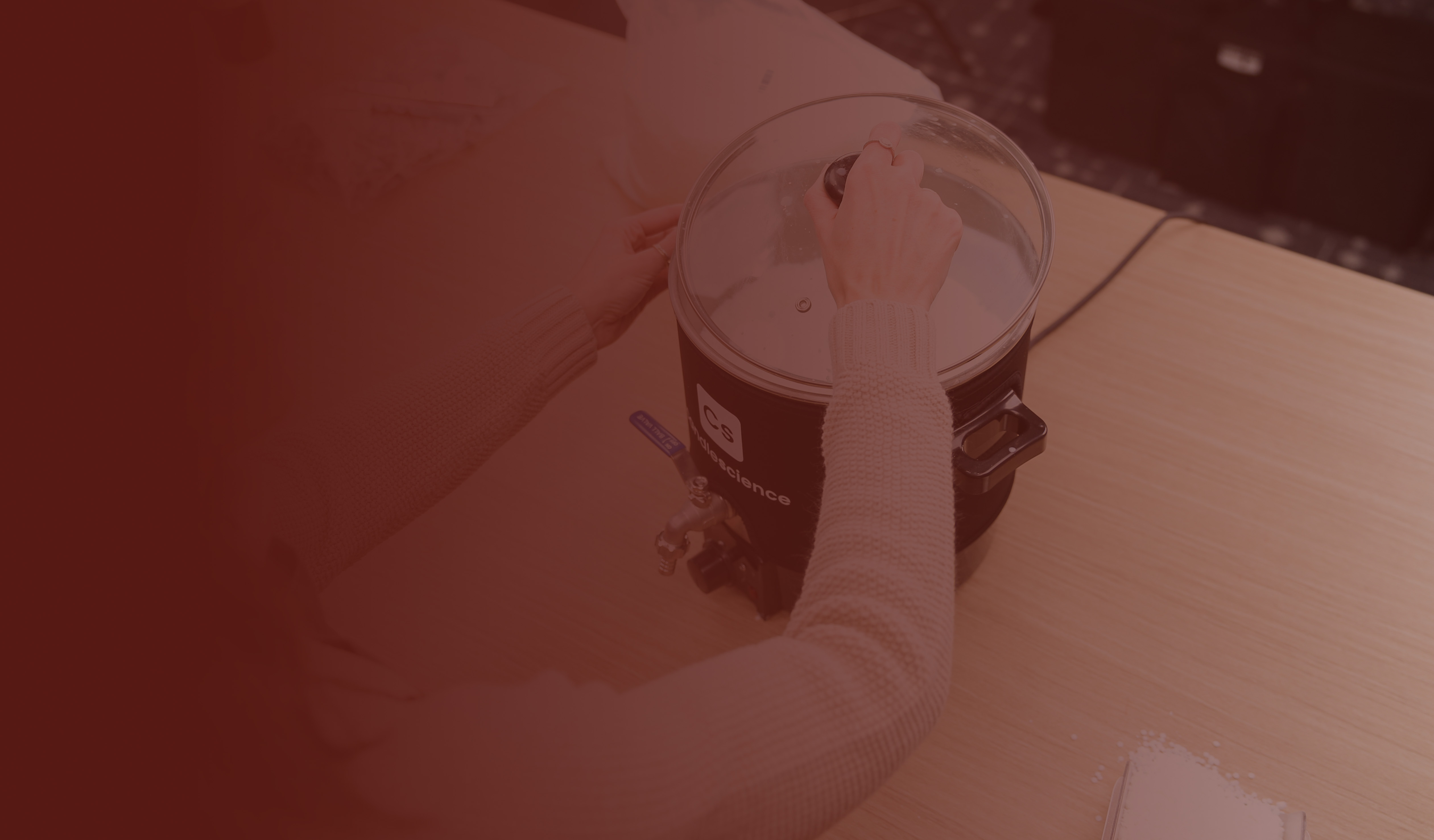 A light-skinned hand places a lid onto a wax melter
