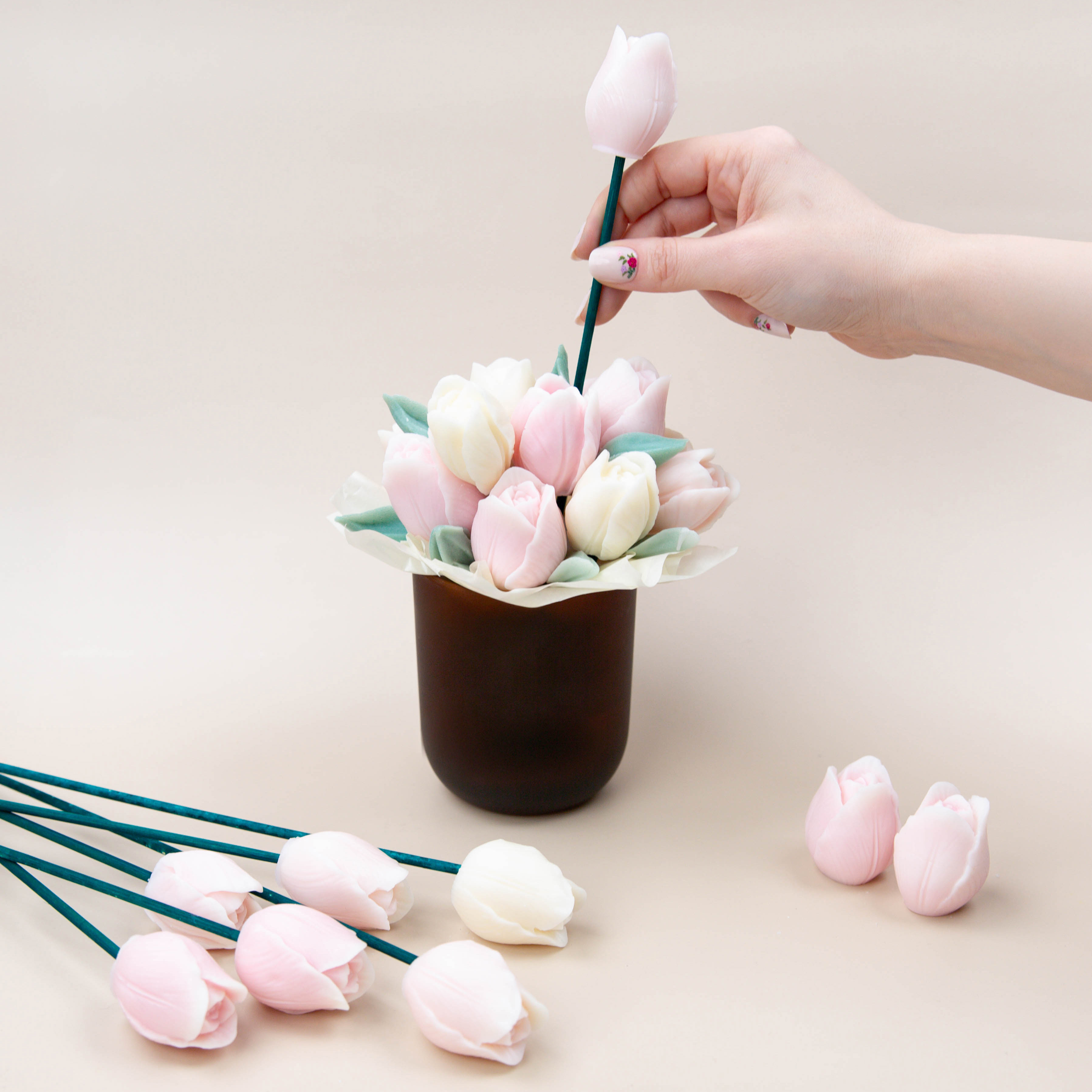 Adding flower wax melts into a container to create a bouquet.