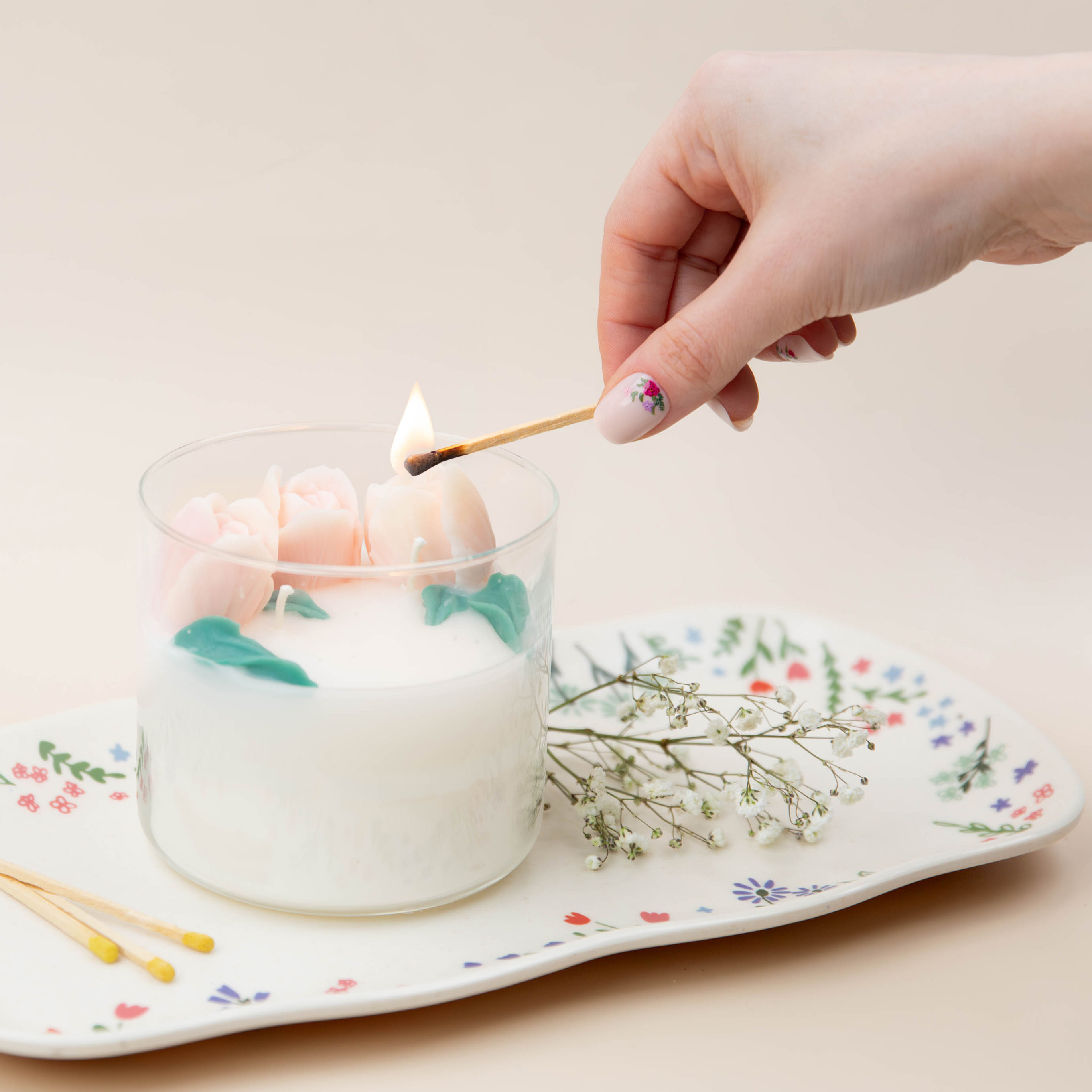 A hand lighting a floral embed candle.