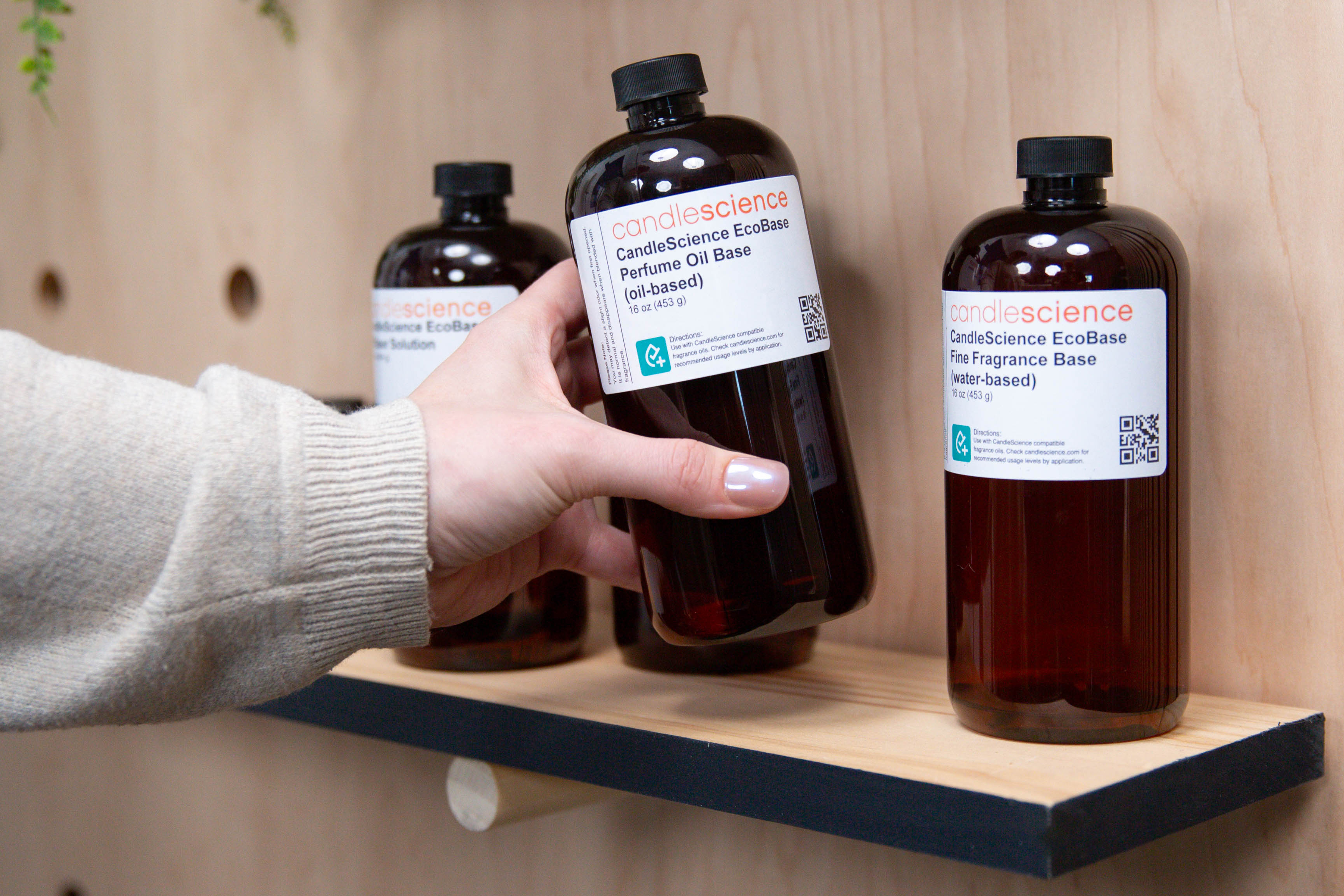 Hand grabbing an EcoBase from a wooden shelf.
