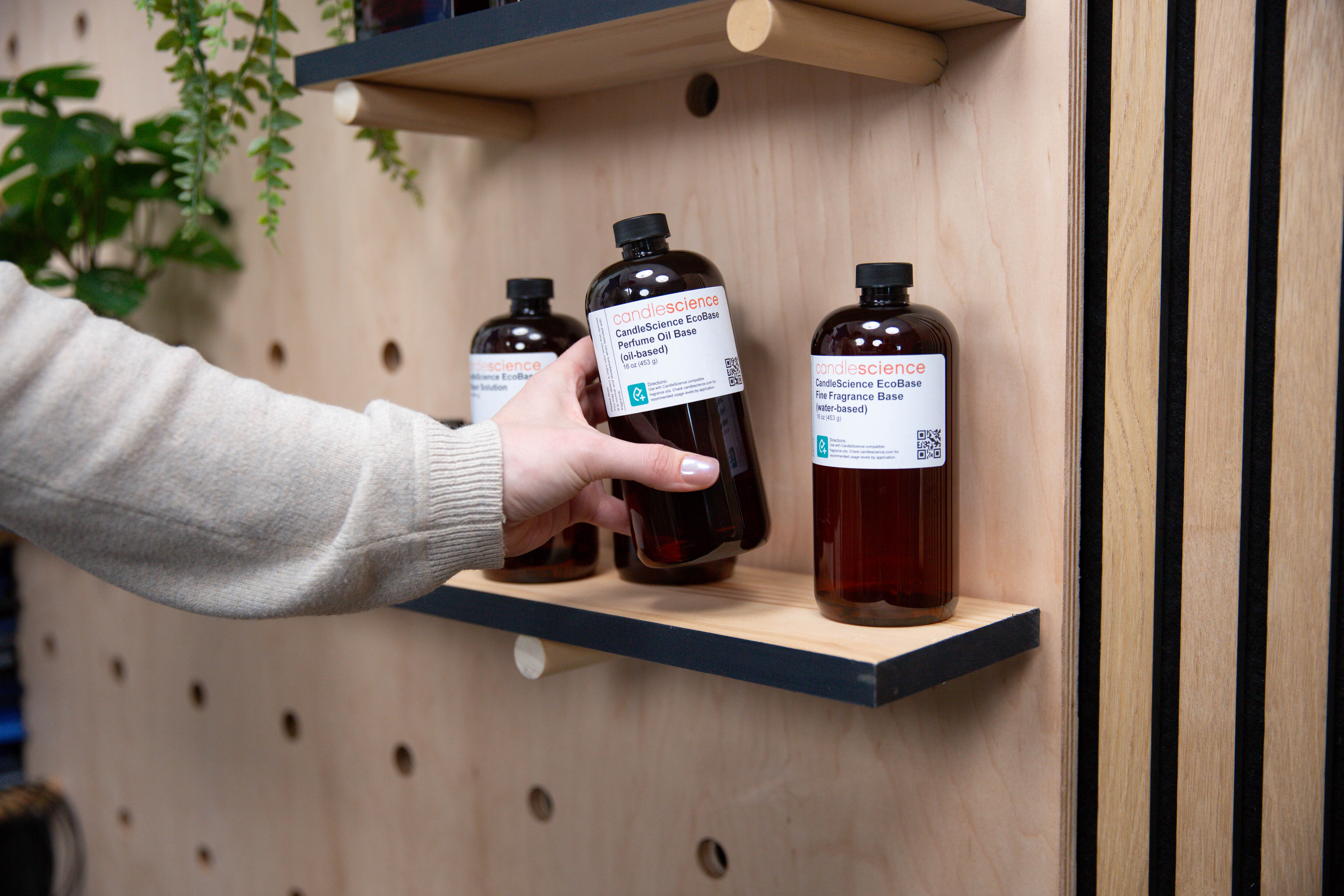 A hand grabbing a CandleScience EcoBase from a shelf.