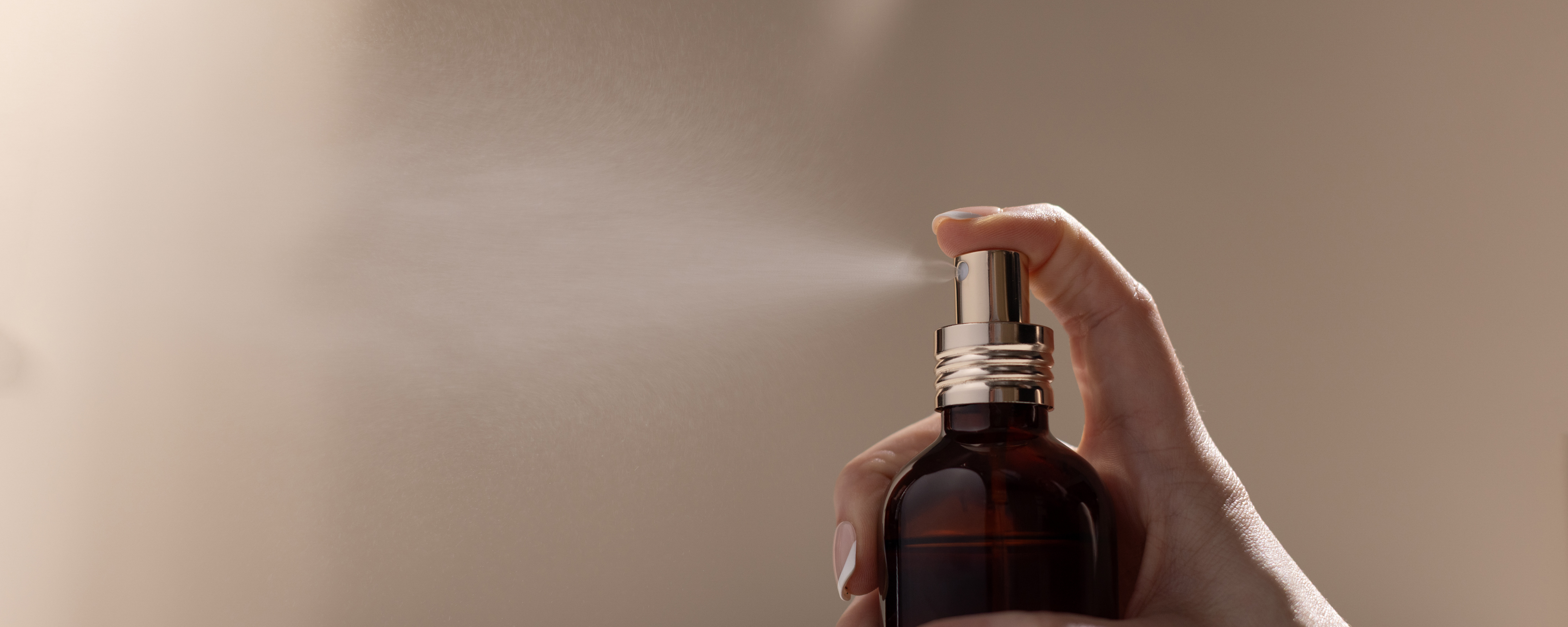 Spraying perfume from a glass amber bottle.