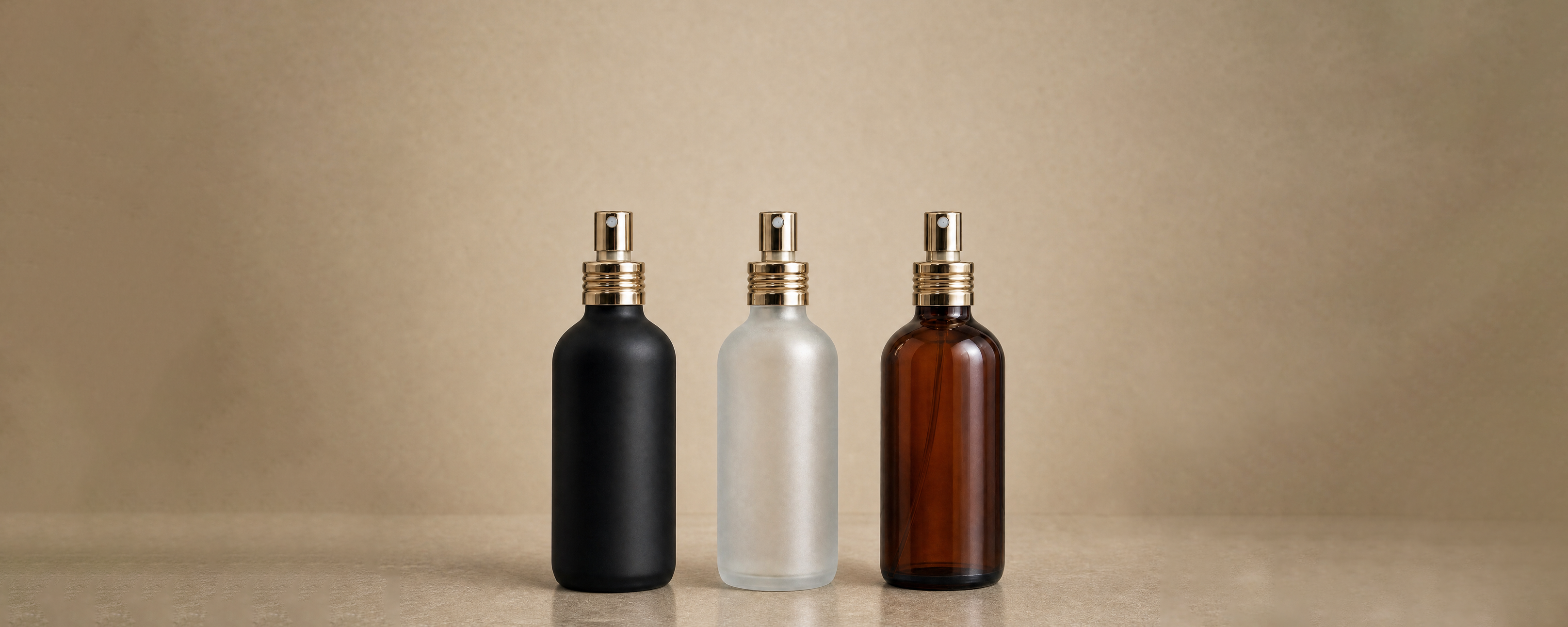 A matte black, frosted, and amber perfume bottle with soft gold pumps.
