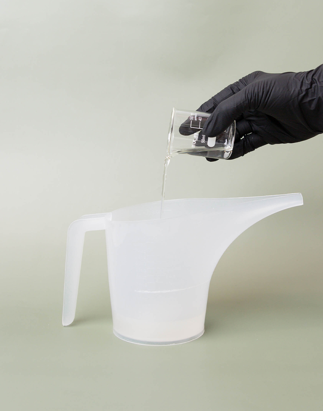 Pouring fragrance oil into funnel pouring pitcher with fine fragrance base.