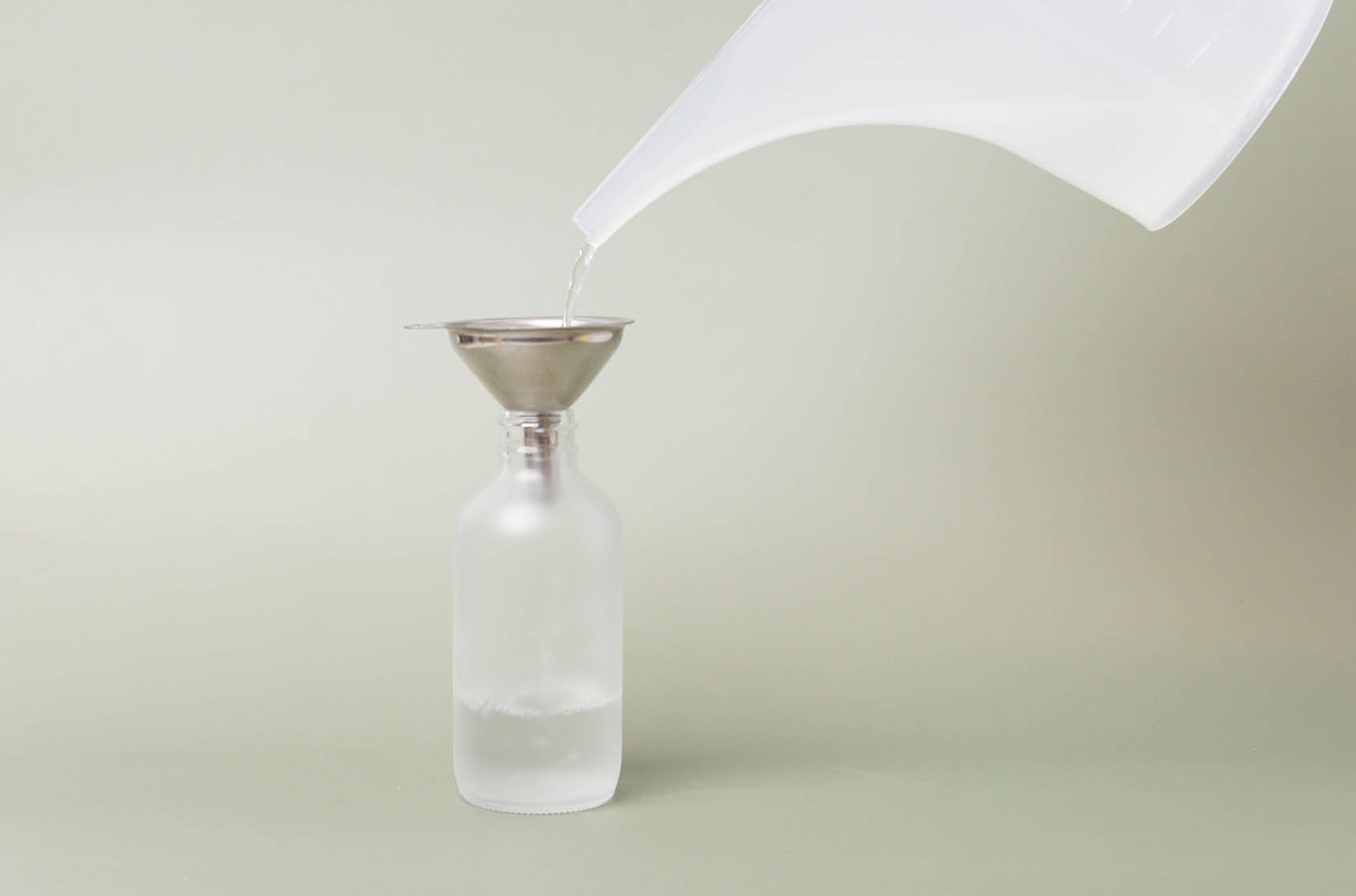 Pouring perfume into glass bottle.
