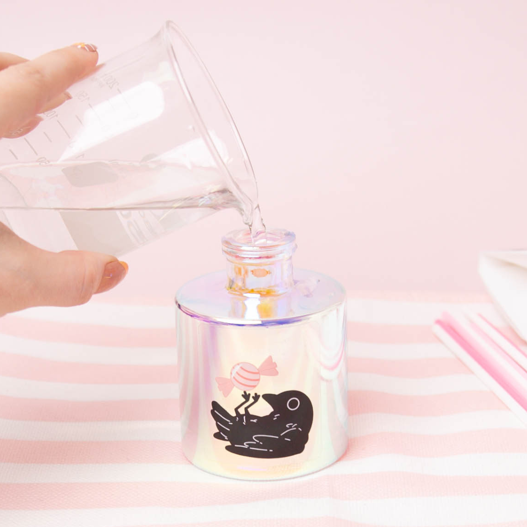 Pouring reed diffuser base and fragrance oil into a prism reed diffuser bottle.