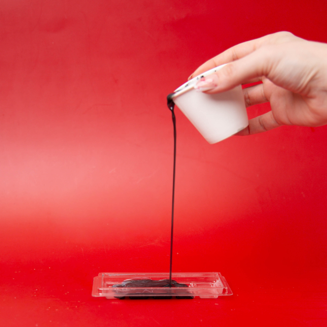 Cup pouring melted wax into a clamshell.