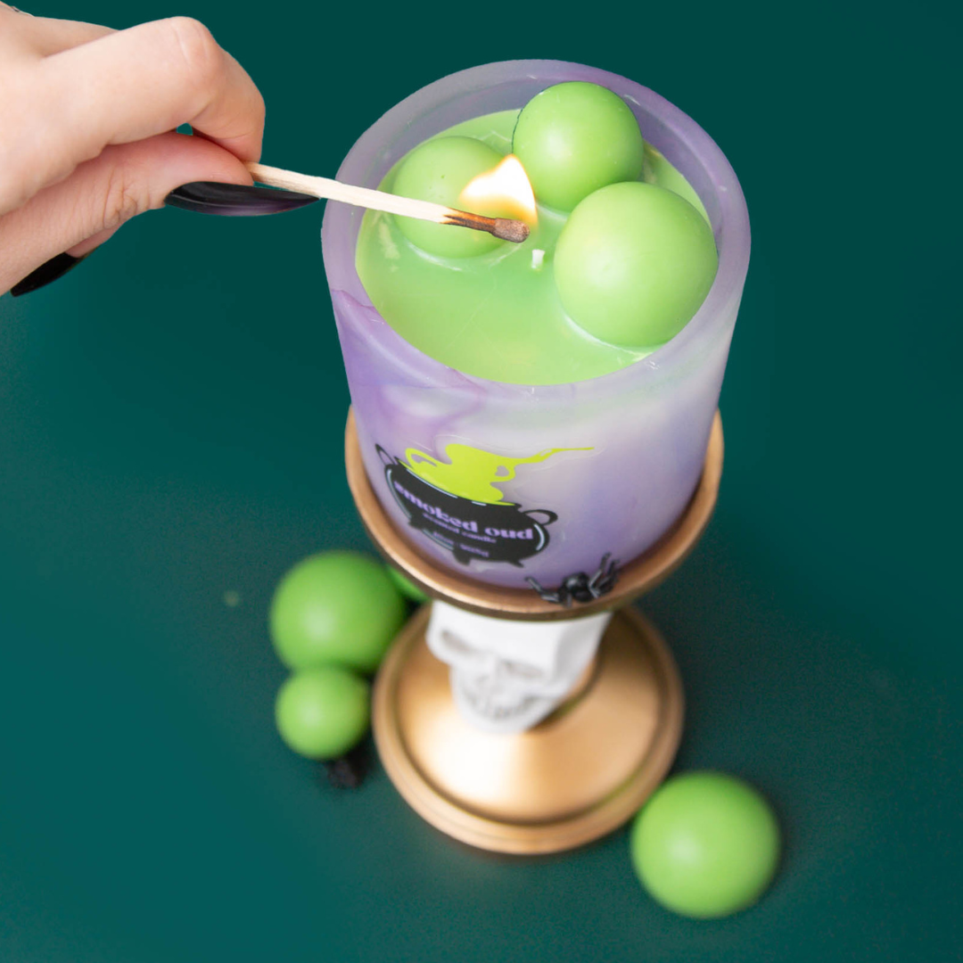 Hand lighting a Halloween green cauldron candle.