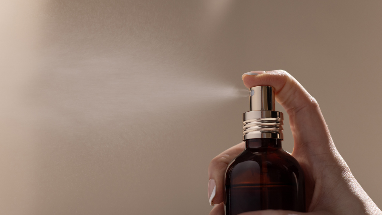 Spraying perfume from a glass amber bottle.