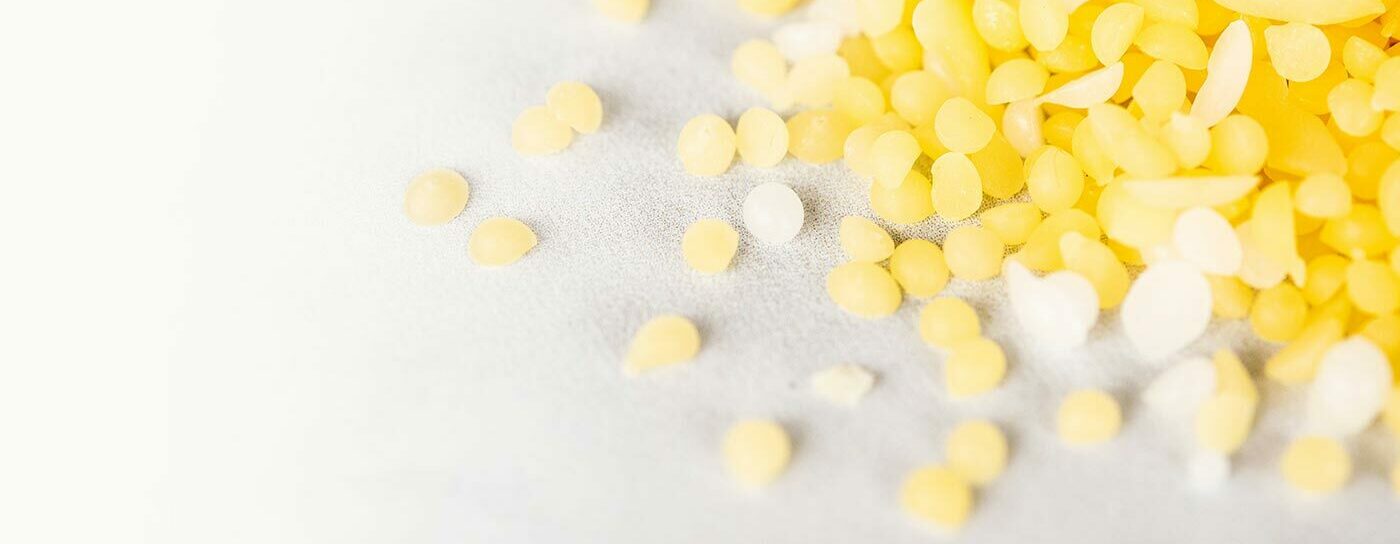 Closeup of yellow and white beeswax pastilles.