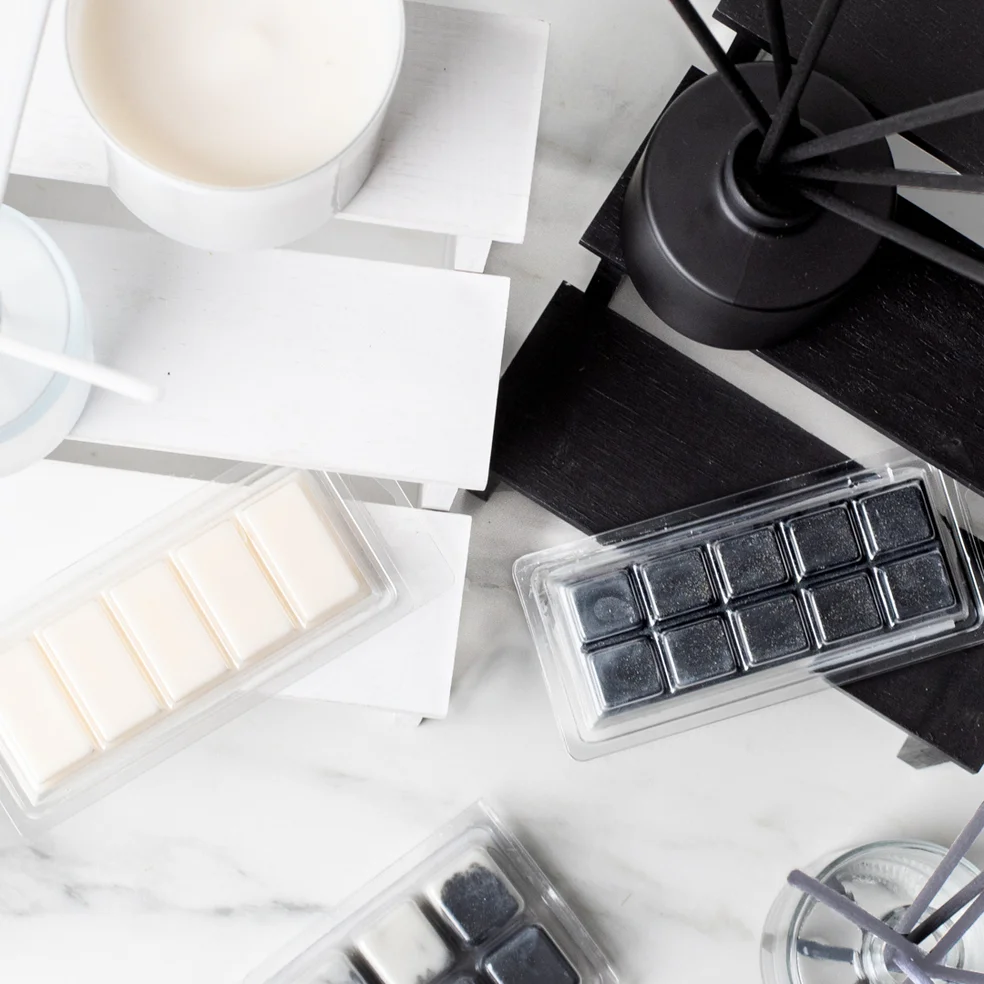 Black and white reed diffusers, wax melts and wickless candles on a marble countertop