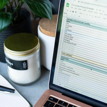 A view of a laptop screen with a spreadsheet and candles next to the laptop