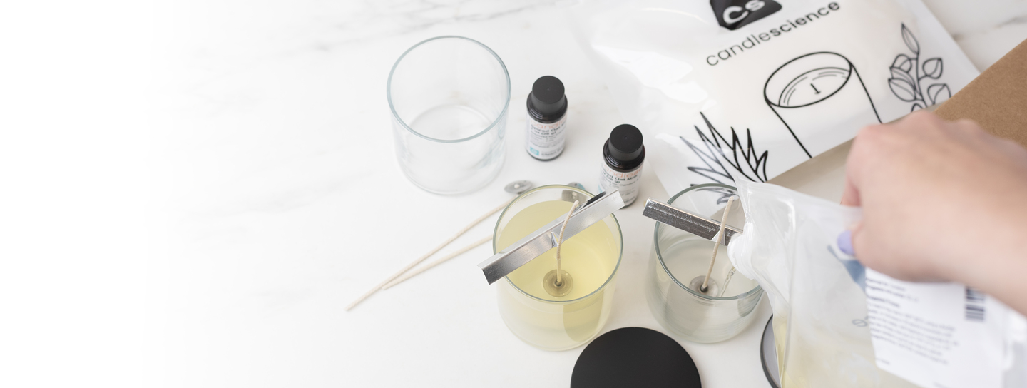 Pouring melted wax into glass candle containers.